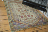 Distressed Oushak rug corner showing faded royal blue border, moss green edge, and reduced fringe.