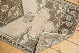 Folded corner of ornate vintage Oushak runner, soft apricot field with bronze-charcoal border.
