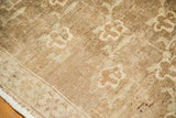 Corner detail of vintage Oushak carpet, showing beige floral lattice pattern and fringe.