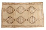 Distressed vintage Oushak rug with six geometric medallions in sand and bark brown tones.
