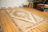 Angled view of the Oushak rug, highlighting oversize tribal medallion and ivory brown palette.