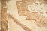 Ivory and soft bronze tribal motifs with diamond spandrel outline on vintage Oushak rug.