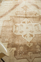 Vintage Oushak carpet with simplistic tribal animal and splayed floral motifs, light brown and ivory.