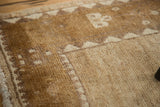 Hand-knotted Oushak rug corner detailing ivory tribal pattern and soft bronze pile.