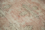 Distressed vintage Oushak runner pile with faded blush, ivory, and quatrefoil floral motifs.