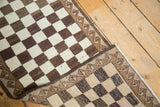 Folded vintage Oushak runner showing textured ivory, brown checker pattern and wave border.
