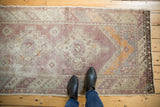 Distressed Oushak runner pile, with faded eggplant, tangerine, and exposed foundation.