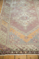 Distressed vintage Oushak runner with faded eggplant field and exposed foundation.