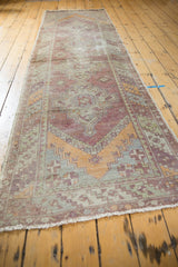 Distressed corner of the vintage Oushak rug, showing purple, orange geometric patterns and secured fringe.