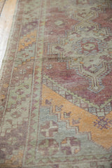 Distressed geometric diagonal border in purple, tangerine, and sea foam green on vintage Oushak runner.