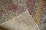 Distressed vintage Oushak runner, its faded purple-green pile and hand-knotted foundation.