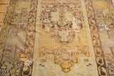 Tattered vintage Oushak rug detail, highlighting holes, exposed foundation, and worn gold tones.