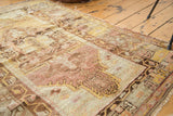 Distressed vintage Oushak rug close-up: worn texture, visible foundation, muted tones.