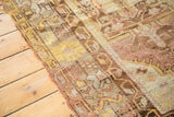 Distressed edge of vintage Oushak rug with tattered pile in gold, brown, and blush.
