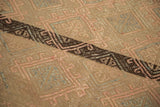 Jijim rug's hand-loomed texture, pink and gray embroidered geometric motifs, dark diagonal stripe.