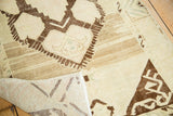 Hand-knotted Oushak rug corner revealing foundation and abrash-rich brown, ivory geometric motif.