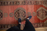 Vintage Oushak runner's abrashed cinnabar red field and tribal serrated medallions.