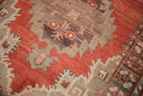 Serrated tribal medallions on an abrashed cinnabar field of a vintage Oushak runner.