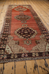 Vintage Oushak runner with abrashed cinnabar field, tribal medallions, and dark chocolate border.