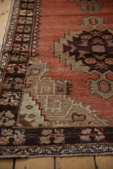 Abrashed cinnabar field, tribal beige spandrel, and floral dark chocolate border on a vintage Oushak rug.