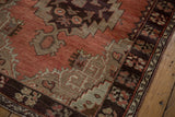 Dark chocolate border with splayed floral bouquets, cinnabar field, and beige tribal spandrel.