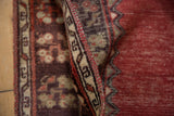 Secured side of vintage Oushak runner, showing beige tribal border and abrashed cinnabar field.