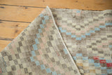 Distressed vintage Oushak rug detail showing geometric diamond pattern and soft pastel tones.