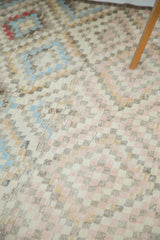 Distressed Oushak rug with geometric checks in soft pastel pink, blue, and cream.