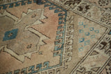 Vintage Oushak rug's plush faded blush field, teal diamond, and hook border.