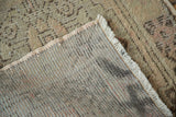 Visible hand-knotted foundation, distressed beige pile, and fringed edge of the Oushak runner.