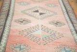 Angled view of vintage Oushak runner with hooked pinwheel gul motifs in faded cinnabar, teal, and beige.
