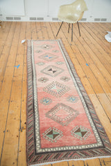 Faded coral vintage Oushak runner showcasing repeating hooked pinwheel guls.