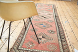 Vintage Oushak runner featuring geometric pinwheel gul motifs in faded blush, teal, and brown.