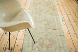 Partial view of a vintage Oushak runner's faded sand field with sea foam starbursts.