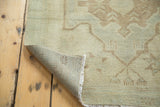 Corner of vintage Oushak runner, showing hand-knotted pile, sea foam green, woven back, and fringed edge.