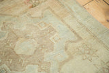 Close-up of vintage Oushak rug's hand-knotted pile, soft faded sand field with subtle starbursts.