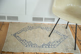 Muted dusty blue medallion on soft sand vintage Oushak rug with distressed texture.