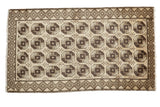 Vintage Turkish Konya runner, neutral ground, dark brown elephant footprint pattern, and checkered border.