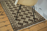 Vintage Konya rug's neutral beige field, dark brown elephant footprint design, checkered border.