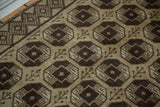 Dark brown elephant footprint design, germinating plants, and checkered border on Konya rug.