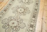 Distressed beige Oushak runner: scalloped medallion, splayed florals, serpentine arabesques.
