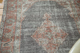 Distressed texture revealing faded brick red patterns on a chocolate brown Oushak.
