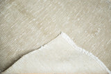 Distressed sand and beige Oushak rug texture, showing its hand-knotted back and fringe.