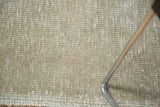 Distressed sand and beige texture of a vintage Oushak runner pile with secured end.