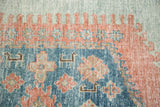 Distressed vintage Oushak rug detail with sky blue, peachy blush, and abstract motifs.