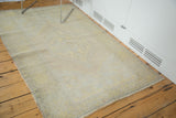 Distressed Oushak rug with faded saffron yellow medallion, floral border, and fringe.