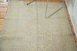 Decorative distressed texture of a vintage Oushak rug in soft saffron and blush.
