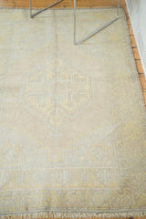 Distressed vintage Oushak rug texture with muted saffron, ivory, silver, and blush tones.