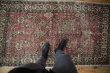 Vintage distressed Oushak rug with cherry red field, curvilinear patterns, and rich texture.
