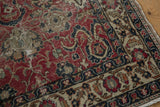 Distressed cherry red Oushak rug's field with scrolling tendrils and beige floral border.